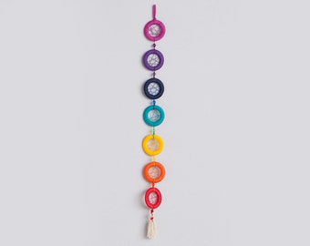 May include: A rainbow-colored dreamcatcher with seven circles, each a different color of the rainbow, hanging from a white tassel.