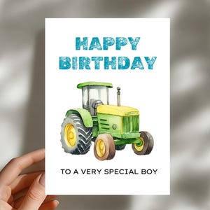 以下が含まれることがあります： 緑と黄色のトラクターの水彩イラストが描かれたバースデーカード。「HAPPY BIRTHDAY」の文字はターコイズ色で、トラクターの下には「TO A VERY SPECIAL BOY」と書かれています。