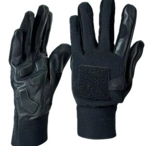May include: Black gloves with leather padding on the palms and knuckles. The gloves have a black fabric back with a velcro patch and a ribbed cuff. The gloves are designed for protection and durability.
