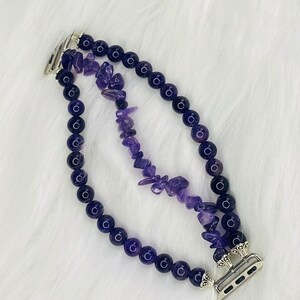 May include: A purple amethyst crystal and black bead Apple Watch band with a silver clasp.