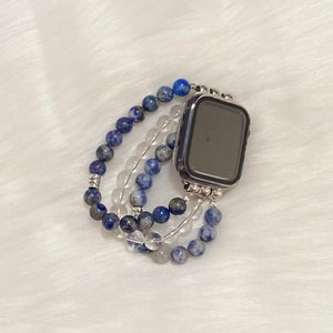 May include: A blue and clear crystal beaded watch band for an Apple Watch.