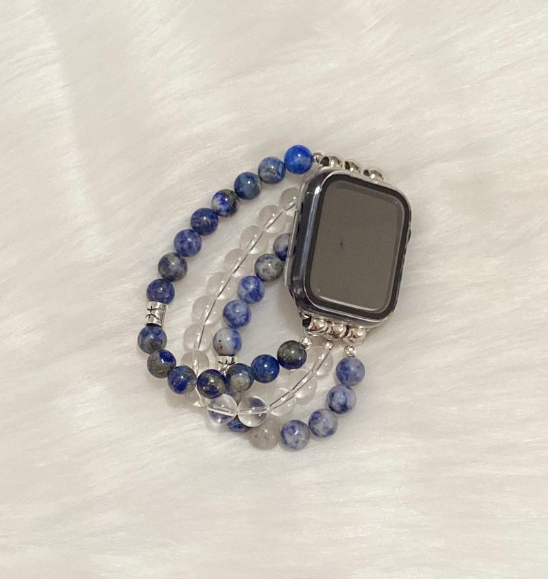 May include: A blue and clear crystal beaded watch band for an Apple Watch.