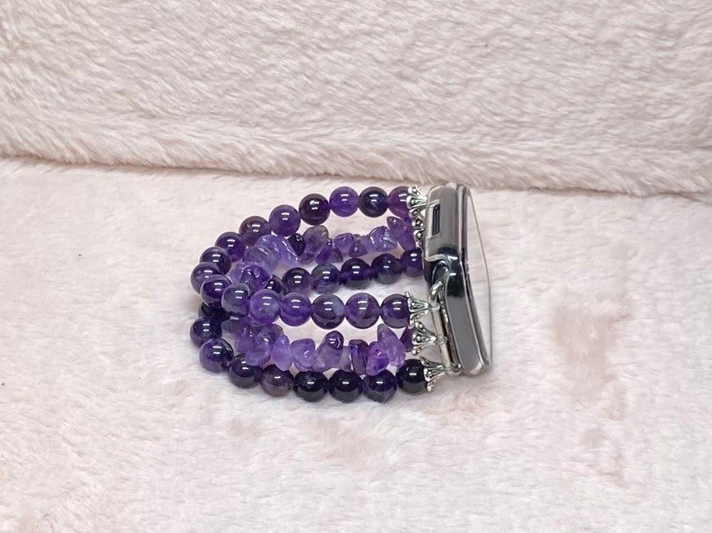 May include: A purple amethyst beaded watch band with silver accents. The band is made of multiple strands of beads and is designed to fit a smartwatch.