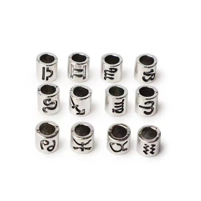 May include: Twelve silver-toned metal beads with zodiac symbols engraved on them. The symbols are: Libra, Gemini, Aquarius, Capricorn, Scorpio, Sagittarius, Virgo, Cancer, Leo, Taurus, Aries, and Pisces.