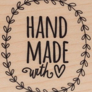 May include: A wooden stamp with a wreath design and the text "HAND MADE with &hearts;".