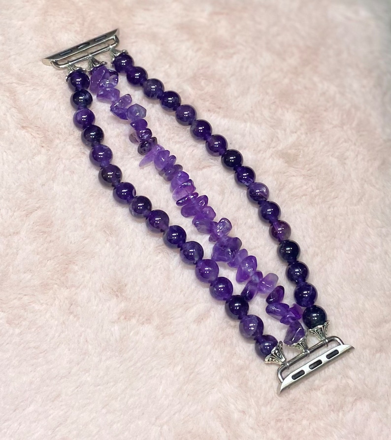 May include: A triple-strand amethyst watch band with a silver watch connector. The band is made of round and irregular shaped amethyst beads.