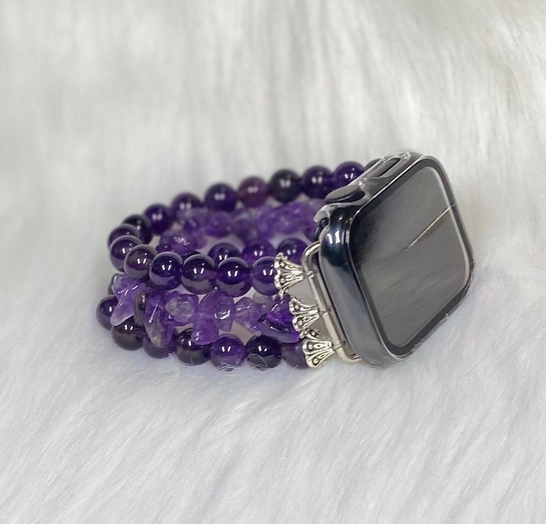 May include: A purple amethyst beaded watch band with a silver clasp and a clear case for an Apple Watch.