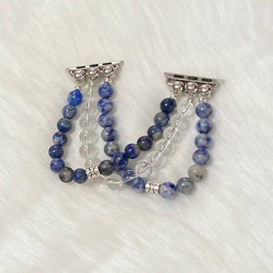 May include: A set of three Apple Watch bands made with blue and white gemstone beads. The bands are connected with silver metal clasps.
