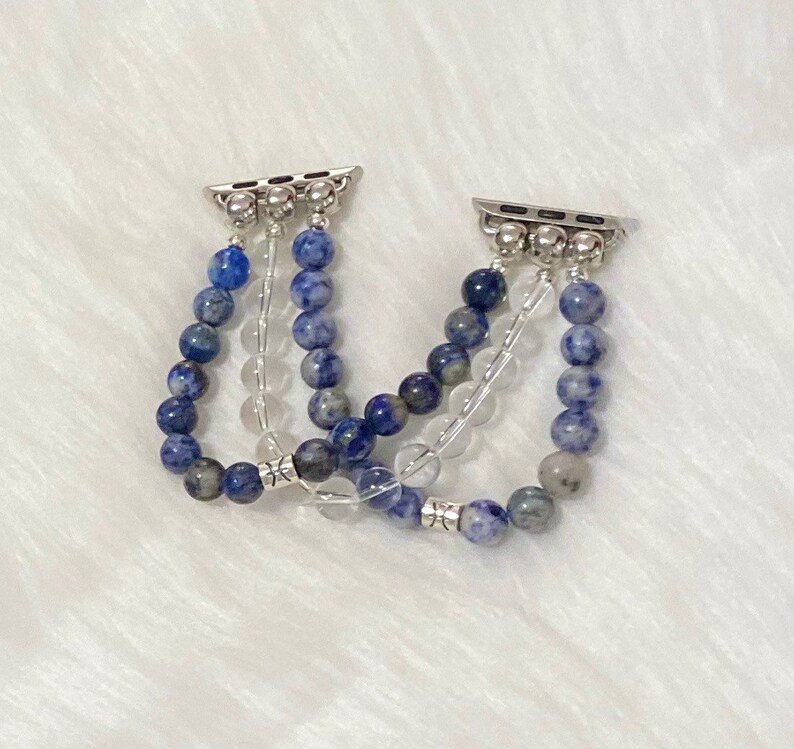 May include: A set of three Apple Watch bands made with blue and white gemstone beads. The bands are connected with silver metal clasps.
