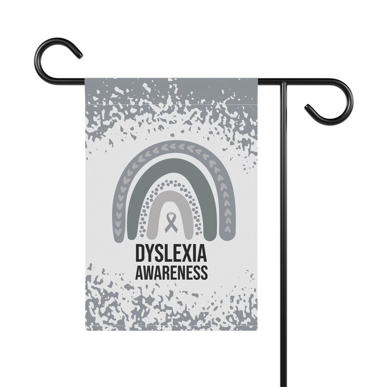 May include: A gray and white garden flag with a rainbow design and the text "Dyslexia Awareness". The rainbow is made up of green, gray, and white stripes. A gray ribbon is in the center of the rainbow.