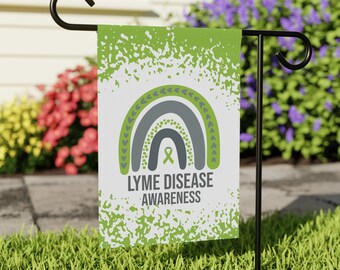 May include: A green and white garden flag with a gray rainbow design and a green ribbon. The text "LYME DISEASE AWARENESS" is printed below the rainbow.