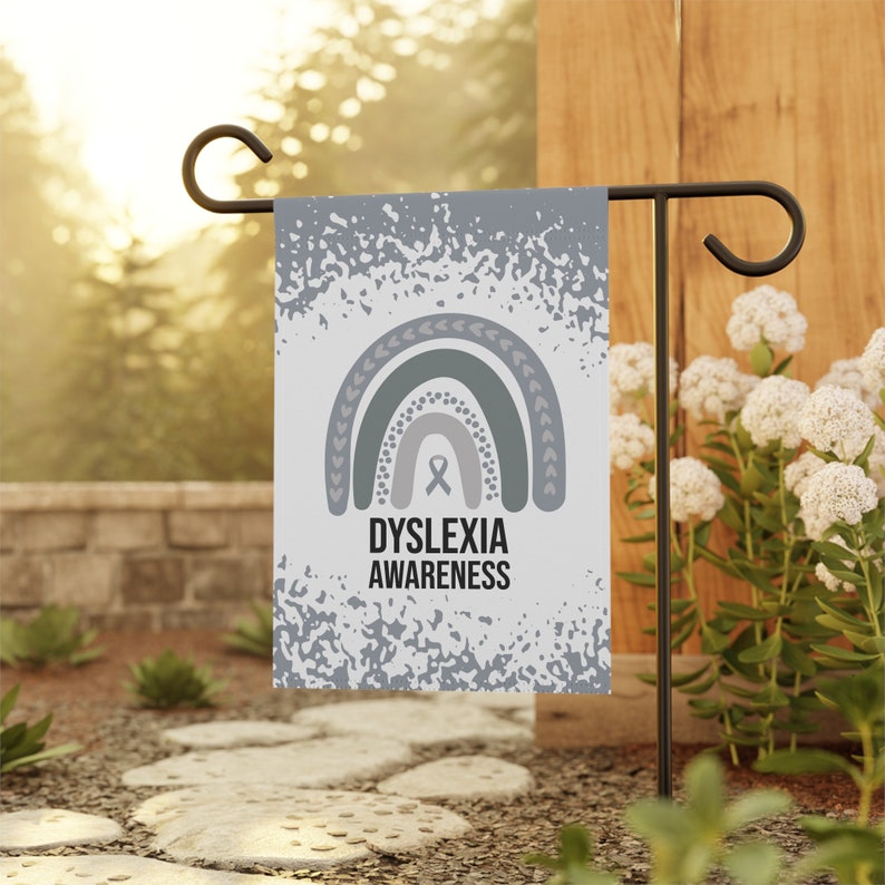 May include: A garden flag with a white background and a gray and green rainbow design. The flag has the text "Dyslexia Awareness" and a gray ribbon.