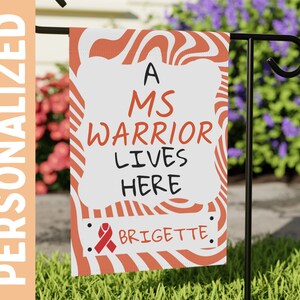 May include: A white garden flag with orange and white stripes. The flag says "A MS Warrior Lives Here" with a red ribbon and the name "Brigitte" at the bottom.