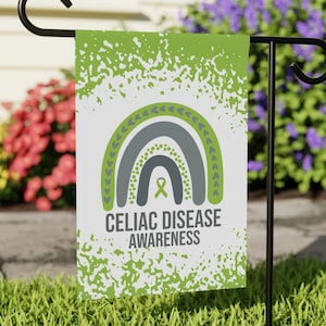 May include: Green garden flag with a white background and a gray rainbow with a green ribbon in the center. The text "Celiac Disease Awareness" is printed below the rainbow.
