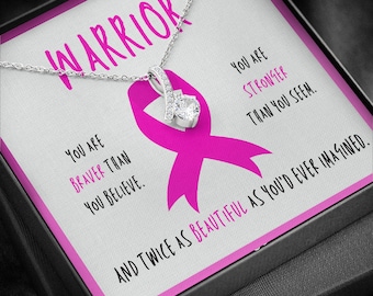May include: A silver necklace with a pink ribbon charm and a clear crystal. The necklace comes in a box with a message that reads "You are braver than you believe. You are stronger than you seem. And twice as beautiful as you'd ever imagined."