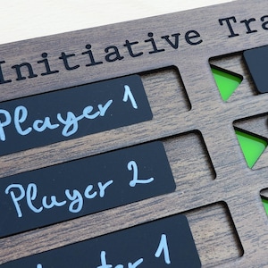 May include: Wooden initiative tracker with the text "Initiative Track" at the top. Black rectangular player labels are labeled "Player 1" and "Player 2" in white script. Green triangle markers are visible in the cut-out slots.