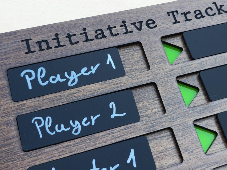 May include: Wooden initiative tracker with the text "Initiative Track" at the top. Black rectangular player labels are labeled "Player 1" and "Player 2" in white script. Green triangle markers are visible in the cut-out slots.