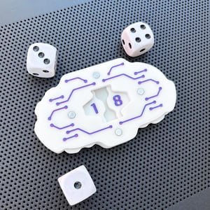 Op de afbeelding: Een witte, wolkvormige spelteller met paarse printplaatpatronen en de cijfers 1 en 8 in een centrale uitsparing. Vier kleine zilveren ronde magneten zijn in het oppervlak verwerkt, vergezeld van drie witte zeszijdige dobbelstenen.