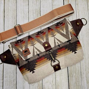 Puede incluir: Ri&ntilde;onera estampada con una correa ajustable de color beige. La bolsa presenta un dise&ntilde;o geom&eacute;trico en tonos marrones, rojos y crema. Tiene detalles de cuero marr&oacute;n y un cierre met&aacute;lico. La correa es beige con herrajes met&aacute;licos.