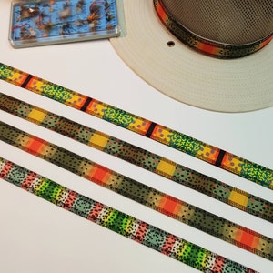 May include: Four different patterned ribbons with a green, orange, yellow, and black colour scheme. The ribbons are laid out horizontally on a white surface.