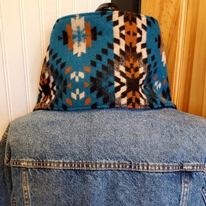 Puede incluir: Una chaqueta vaquera azul con un cuello de patr&oacute;n colorido. El cuello est&aacute; hecho de una tela suave y tejida con dise&ntilde;os geom&eacute;tricos en tonos marrones, blancos y negros.