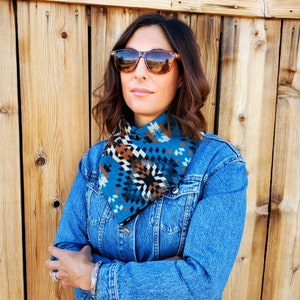 Puede incluir: Una mujer con una chaqueta vaquera azul y una bufanda estampada en azul, marr&oacute;n y blanco alrededor del cuello. Lleva gafas de sol de carey marr&oacute;n.