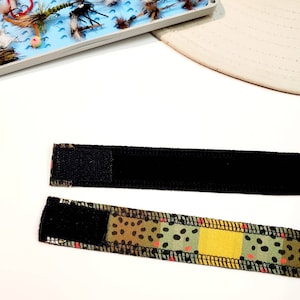 May include: Two black and brown patterned fabric bands with black velcro closures. The bands are designed to be worn around the wrist or arm.