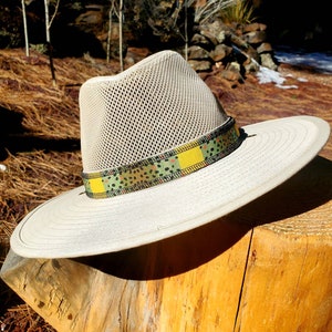 May include: A white mesh hat with a wide brim and a patterned band. The band is green, yellow, and brown with a speckled pattern.