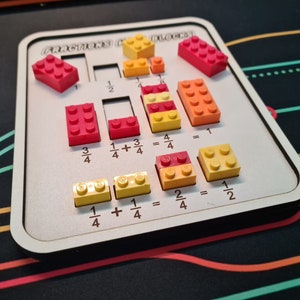 May include: A wooden educational toy with colorful building blocks for learning fractions. The board features red, orange, and yellow blocks arranged to demonstrate fraction concepts. Text on the board reads "FRACTIONS (WITH) BLOCKS!"