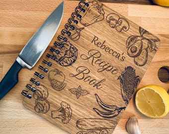 Może przedstawiać: Drewniana książka kucharska ze spiralnym oprawą. Okładka jest grawerowana różnymi warzywami i tekstem "Rebecca's Recipe Book".