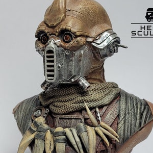 May include: A detailed bust of a fictional character with a weathered, brown and grey helmet, a brown and tan scarf, and a chest piece with bone-like accents. The character has a weathered, brown and grey helmet with a silver face mask and two orange eyes.