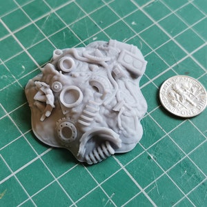 Puede incluir: Un modelo gris impreso en 3D de una pila de chatarra y engranajes. El modelo es aproximadamente del tamaño de una moneda de diez céntimos de euro.