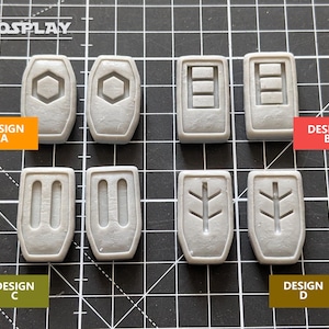 May include: Eight gray plastic molds with different designs. The designs are labeled "Design A", "Design B", "Design C", and "Design D".
