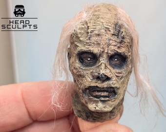 Puede incluir: Una escultura de cabeza en miniatura altamente detallada y texturizada, con una tez bronceada y desgastada, ojos oscuros hundidos y cabello claro escaso. El texto HEAD SCULPTS con un icono de stormtrooper es visible en la esquina superior izquierda.