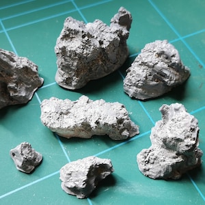 May include: A set of seven grey, textured, rock-like objects. The rocks are various sizes and shapes, and they appear to be made of a lightweight material.