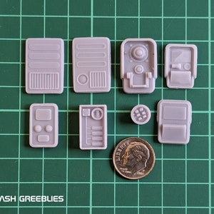 Könnte beinhalten: Acht graue Kunststoffplatten mit verschiedenen Designs, darunter ein Bedienfeld, eine Türplatte und eine Lüftungsplatte. Die Platten haben einen Durchmesser von etwa 2,5 cm. Eine deutsche Zehn-Cent-Münze dient als Größenvergleich.