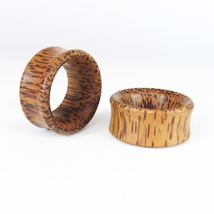 May include: Two wooden ear gauges with a brown and tan striped pattern.