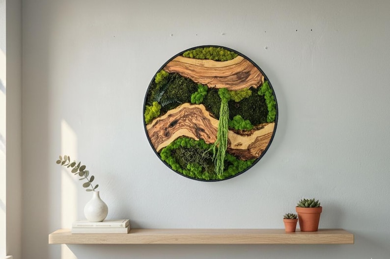 May include: Round wall art with a black frame, featuring a natural moss and wood design. The artwork incorporates various shades of green moss and light brown wood elements. A decorative piece for home decor.