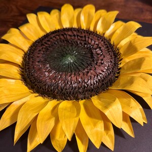 Peut inclure: Un tournesol artisanal avec des p&eacute;tales jaune vif et un centre brun fonc&eacute;. Le centre du tournesol a un aspect textur&eacute;, avec un centre vert fonc&eacute;. Les p&eacute;tales sont superpos&eacute;s, cr&eacute;ant un effet complet et dimensionnel. Le tournesol est un objet d&eacute;coratif.