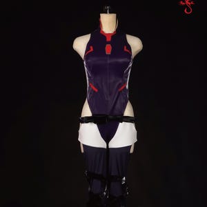 May include: A purple and red bodysuit with a white skirt and black leggings. The bodysuit has a high collar and a red design on the front. The skirt is short and has a white trim. The leggings are long and have a black trim.