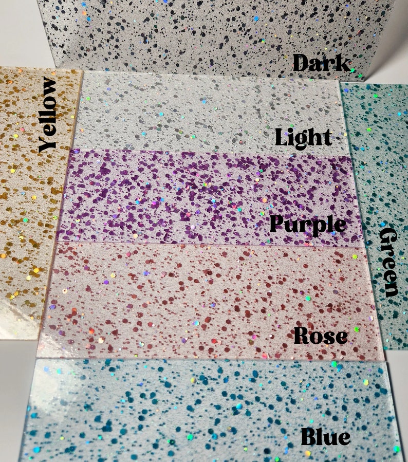 Puede incluir: Primer plano de siete papeles de purpurina de diferentes colores. Los colores son amarillo, blanco, morado, rosa, azul, verde claro y verde oscuro.