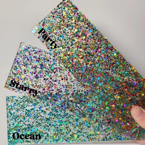 Puede incluir: Tres l&aacute;minas de resina epoxi transparente con purpurina iridiscente. La l&aacute;mina superior tiene la palabra "Party" impresa. La l&aacute;mina intermedia tiene la palabra "Starry" impresa. La l&aacute;mina inferior tiene la palabra "Ocean" impresa.
