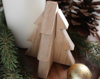 Op de afbeelding: Een houten kerstboomversiering met een gouden ornament op een houten dienblad met dennentakken en een witte kaars.