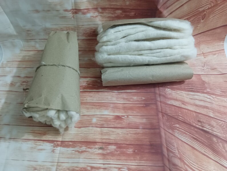 Puede incluir: Dos rollos de bolas de algod&oacute;n blancas envueltos en papel marr&oacute;n. Las bolas de algod&oacute;n est&aacute;n apiladas y listas para usar.