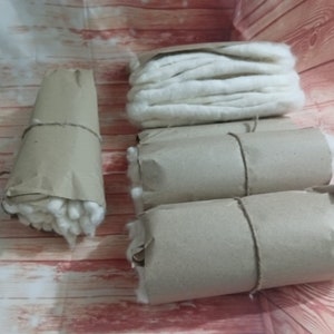 Puede incluir: Cuatro rollos de bolas de algod&oacute;n blancas envueltos en papel marr&oacute;n. Las bolas de algod&oacute;n est&aacute;n bien apretadas y el papel est&aacute; atado con una cuerda.