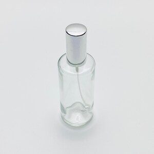 May include: A clear glass bottle with a silver spray top. The bottle is empty and ready to be filled.