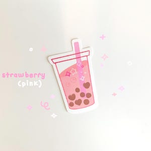 May include: Pink and white sticker of a pink bubble tea with brown boba pearls and a pink straw. The text "strawberry (pink)" is written below the bubble tea.