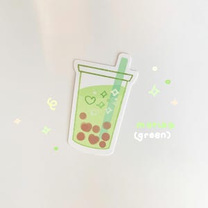 May include: Green bubble tea sticker with a green straw and brown boba pearls. The sticker has a white background and the text "matcha (green)" is written below the bubble tea.