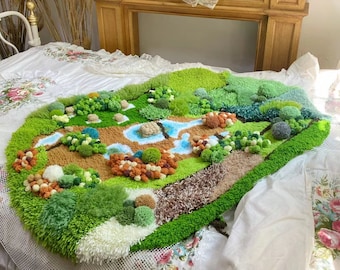 Op de afbeelding: Een groen, bruin en wit tapijt met een landschapsontwerp. Het tapijt is gemaakt van garen en heeft een textuur. Het ligt op een wit bed met een bloemenpatroon.