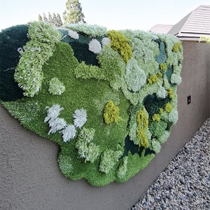 May include: A large, green, white, and yellow wall hanging made of fluffy yarn. The wall hanging is shaped like a cloud and has a textured, organic look.